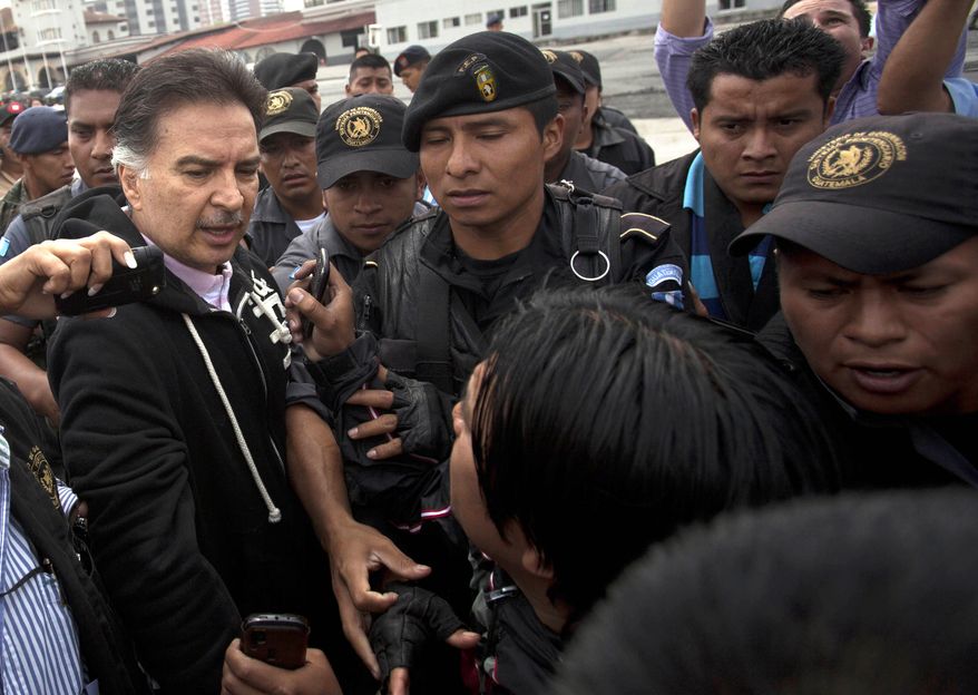 Alfonso Portillo (left), former president of Guatemala, speaks to the press May 24, 2013, as he is led by police to an aircraft that will fly him to the United States from Guatemala City. Portillo was extradited to the United States to face charges of laundering $70 million in Guatemalan funds through U.S. bank accounts. (Associated Press)