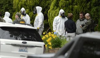 **FILE** During the execution of a search warrant, members of the joint federal hazmat team, FBI and local law enforcement gather in front of the Osmun Apartments in Spokane, Wash., on May 18, 2013. The search warrant is in connection with ricin-laced letters intercepted at a Post Office facility in Spokane earlier in the week. (Associated Press/TheSpokesman-Review)