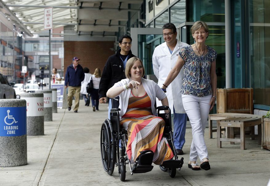 Boston Marathon bombing survivor Erika Brannock, 29, a Baltimore area preschool teacher who lost a leg, is accompanied by her mother, Carol Downing, right, as she is released from Beth Israel Deaconess Medical Center in Boston, Monday, June 3, 2013. Brannock and her sister, Nicole Gross, were waiting at the finish line for their mother to finish the race when the bombs went off. Walking behind are Dr. Alok Gupta, left, and Dr. Edward Rodriguez. (AP Photo/Elise Amendola)