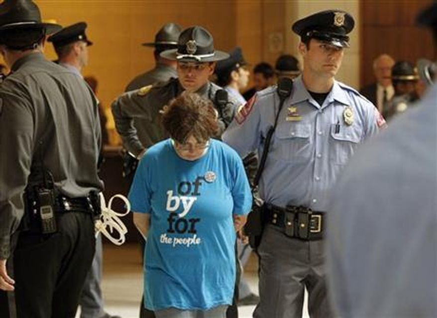 General Assembly Police and Raleigh Police escort a woman away after she was arrested at the Legislative Building as the Monday protests are held at the General Assembly in Raleigh, N.C. on Monday, June 3, 2013. (Associated Press)