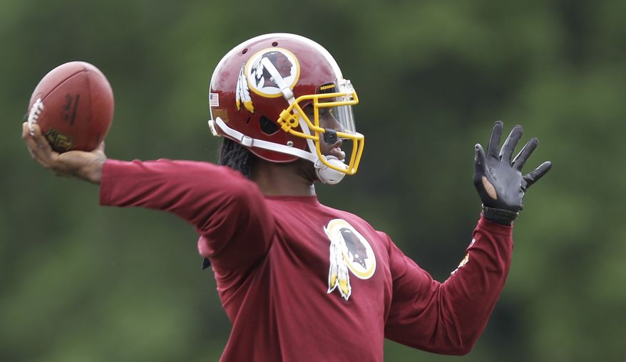 Washington Redskins quarterback Robert Griffin III throws a pass during team practice at Redskins Park, Thursday, June 6, 2013, in Ashburn, Va. (AP Photo/Luis M. Alvarez)