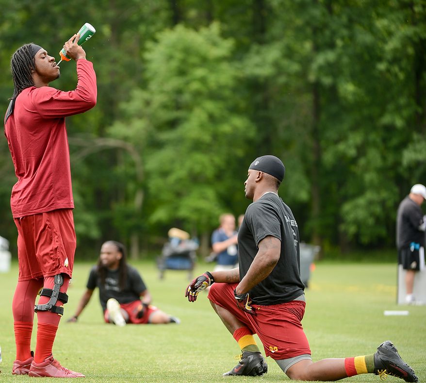 Washington Redskins quarterback Robert Griffin III (10), left, gets a drink from Washington Redskins tight end Fred Davis (83), right, before practice during a NFL football organized team activity at Redskins Park, Ashburn, Va., Thursday, June 6, 2013. (Andrew Harnik/The Washington Times)