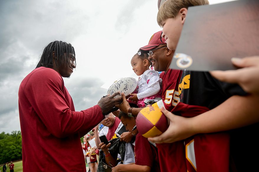 Washington Redskins quarterback Robert Griffin III (10) signs an autograph for Jordan Johnson, center, following a NFL football organized team activity at Redskins Park, Ashburn, Va., Thursday, June 6, 2013. (Andrew Harnik/The Washington Times)