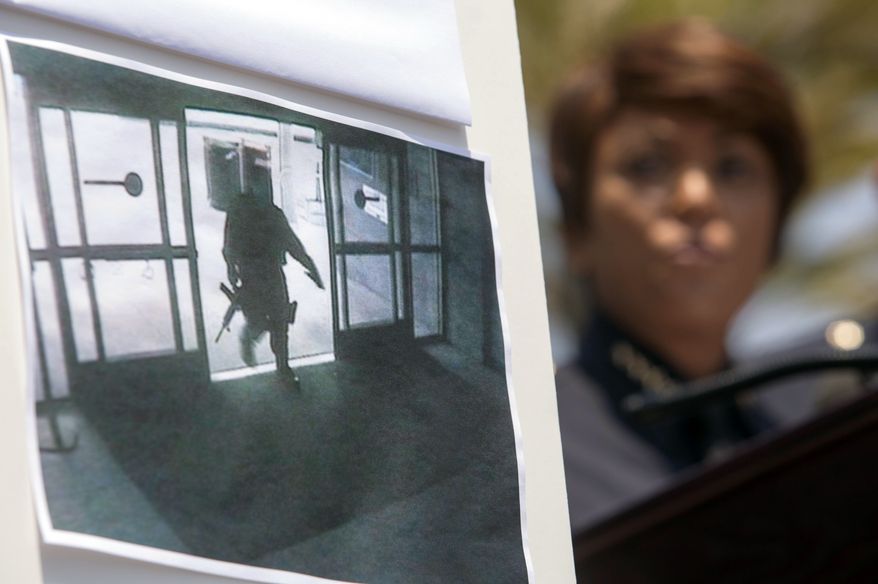 A picture of the shooting suspect entering the Santa Monica College library is seen as Chief Jacqueline Seabrook of the Santa Monica Police Department speaks during a news conference on Saturday June 8, 2013, in Santa Monica, Calif., to discuss the shootings that left five people dead, including the shooter, near the college Friday. (AP Photo/Ringo H.W. Chiu)