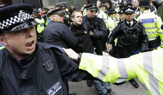 A demonstrator is taken to a police vehicle after he was detained during a protest in London on Tuesday, June 11, 2013. The protesters were railing against the G-8 summit in Northern Ireland next week. (AP Photo/Alastair Grant)
