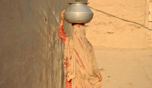 A woman returns home after fetching water in a village in Mohmand Agency (FATA). It is a woman&amp;#226;&amp;#8364;&amp;#8482;s task to collect and carry water for domestic use. Village houses usually do not have a direct water supply. Photo / Alamgir Khan