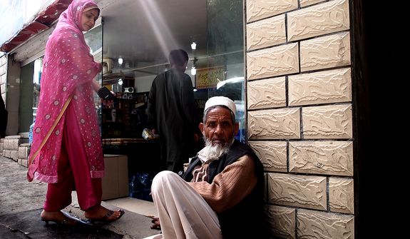 In the famous summer resort of Murree, an old man sits at the door of a shop at the mall waiting for someone to give him money. The woman entering the shop wants to give him money, but he is looking into the camera to get his photo taken. Photo / Rizwan Bhittani