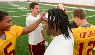Washington Redskins offensive coordinator Kyle Shanahan, second from right, Washington Redskins quarterback Robert Griffin III (10), center, and the other quarterbacks come together at the conclusion of practice during mini camp at Redskins Park, Ashburn, Md., Tuesday, June 11, 2013. (Andrew Harnik/The Washington Times)