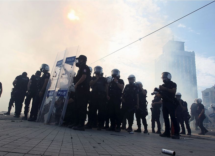 Police stand amid tear gas during clashes with protesters in Taksim Square in Istanbul on Tuesday, June 11, 2013. Hundreds of police in riot gear forced through barricades and pushed many of the protesters who had occupied the square for more than a week into a nearby park. (AP Photo/Thanassis Stavrakis)