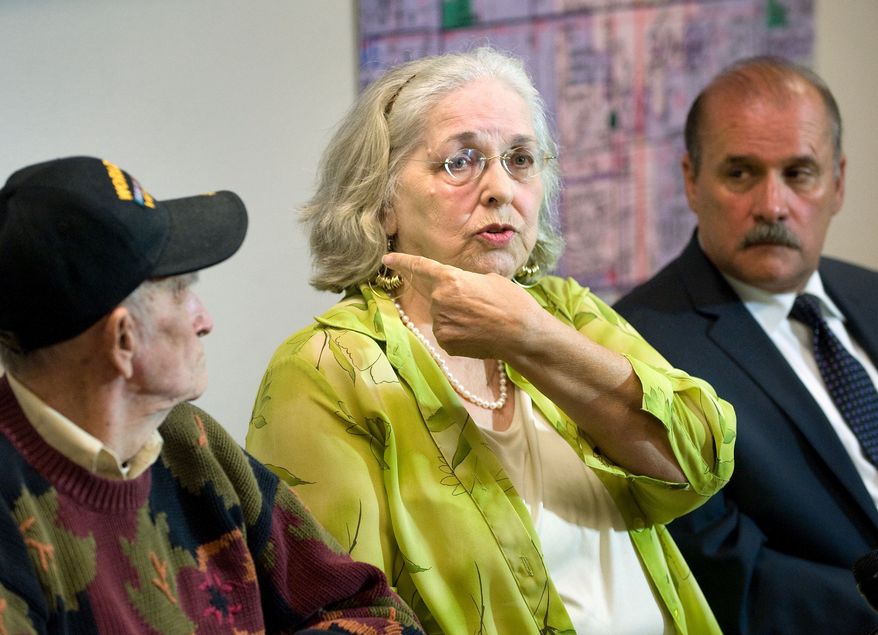 Jan Cooper, 72, talks to the media as her husband Bob, 85, left, and OC Sheriff's spokesman Jim Amormino listen during a news conference at the Sheriff's Department station in Stanton on Tuesday, June 11, 2013. Jan Cooper showed where the Sheriff's estimated the bullet traveled, based on the size of the suspect and the damage to her sliding glass door, when she scared off an intruder at her home in unincorporated Anaheim on Sunday, June 9, by firing a shot from her .357 Magnum during the attempted break-in. (AP Photo/The Orange County Register, Paul Bersebach)