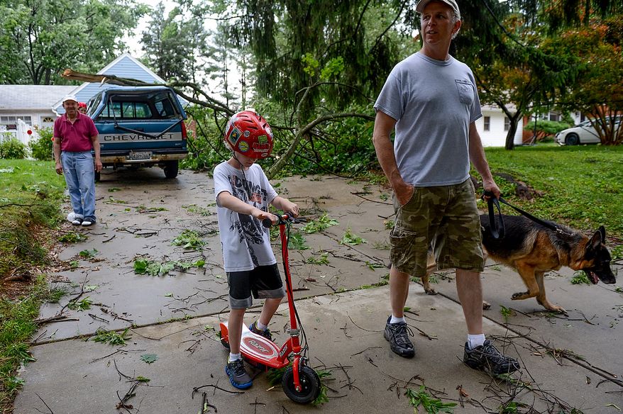 Steve Roper and his son Ely, 9, bring their dog, Maverick, out with them as they check in on Jose Torres, left, who sustained damage to his truck from a large branch which fell outside his house in the Cloverly neighborhood after severe storms came through the region bringing heavy rain and winds, Silver Spring, Md., Thursday, June 13, 2013. (Andrew Harnik/The Washington Times)