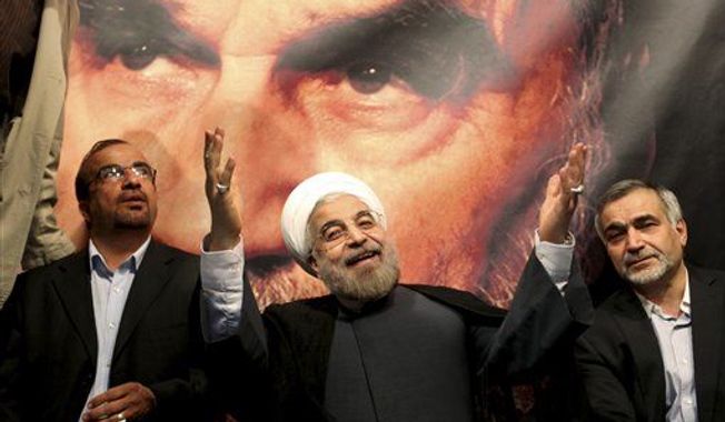 ** FILE ** In front of a portrait of the late Iranian revolutionary founder Ayatollah Khomeini, presidential candidate Hasan Rowhani, a former top nuclear negotiator, center, gestures to his supporters at a rally in Tehran, Iran, Saturday, June 1, 2013.