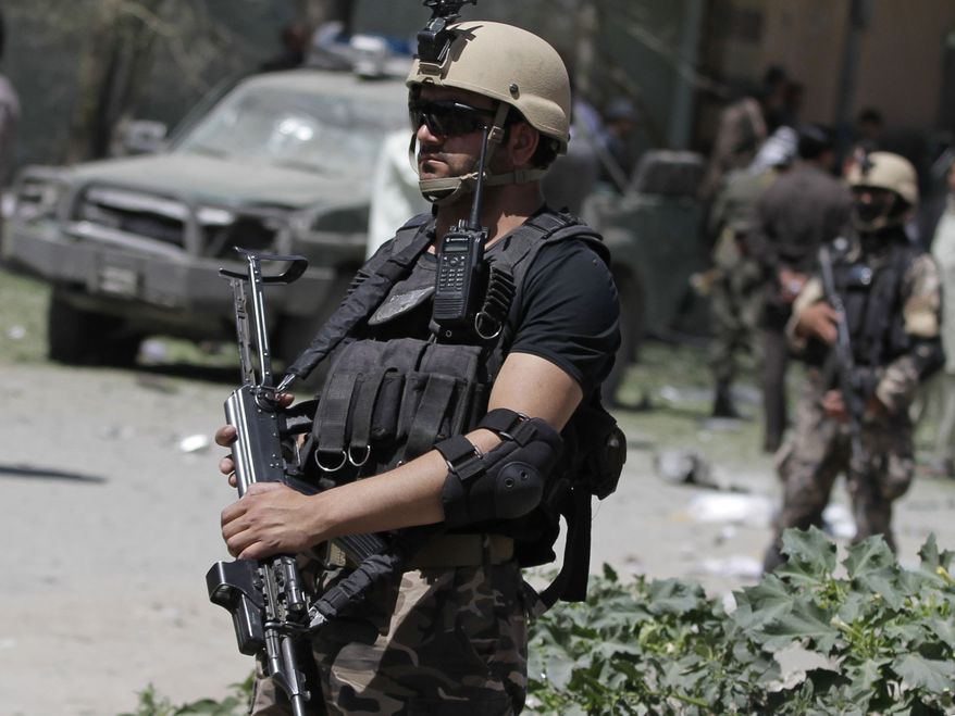 **FILE** Afghan security forces members stand guard at the site of a blast near the Afghan Independent Human Rights Commission in Kabul, Afghanistan, on June 18, 2013. The large bomb exploded in the Afghan capital as the international military coalition hands over responsibility for fighting the Taliban insurgency to the nascent national army and police they have been training. (Associated Press)
