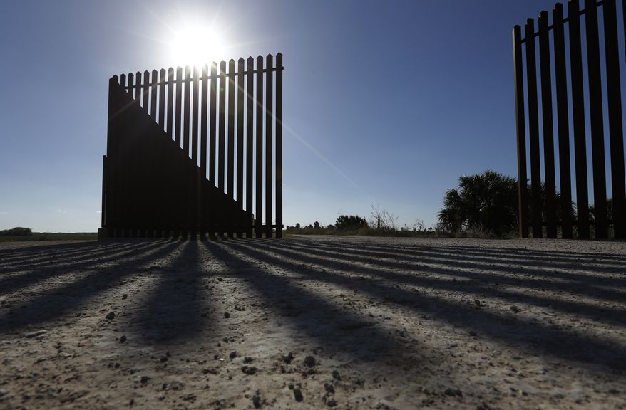 **FILE** The sun casts a shadow on the border fence that passes through the Nature Conservancy's southernmost preserve in Brownsville, Texas, on Sept. 4, 2012. (Associated Press)