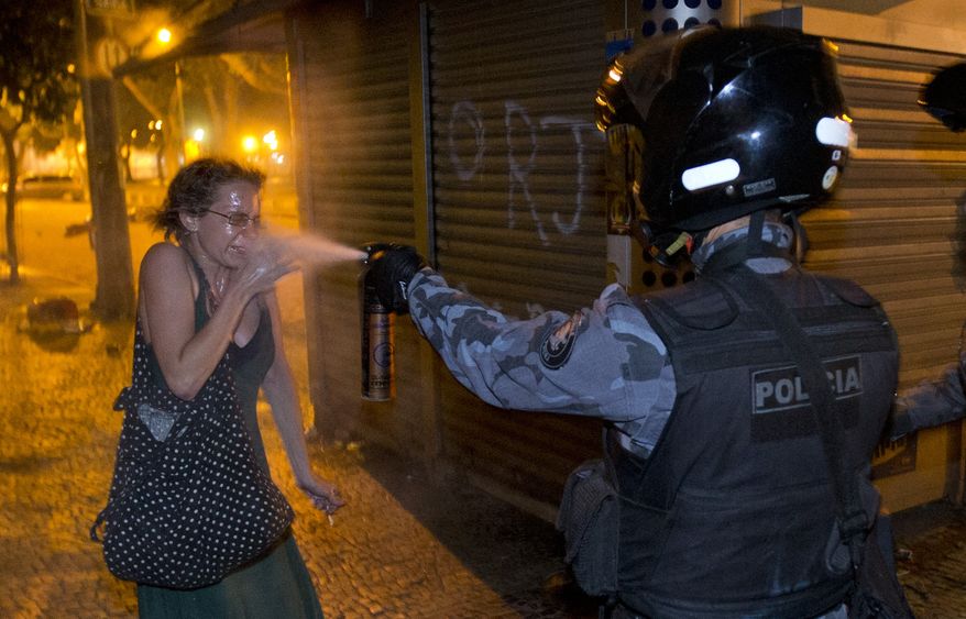 **FILE** A military police officer pepper-sprays a protester during a demonstration in Rio de Janeiro on June 17, 2013. Protesters massed in at least seven Brazilian cities for another round of demonstrations voicing disgruntlement about life in the country, raising questions about security during big events such as the ongoing Confederations Cup and a papal visit the following month. (Associated Press)