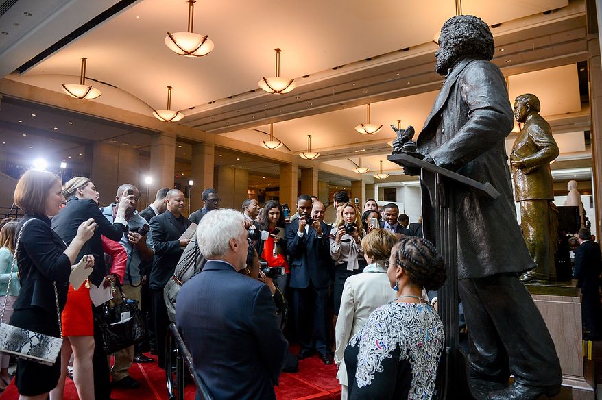 Visitors to a congressional ceremony to commemorate the dedication and unveiling of a statue of Frederick Douglass crowd around the statue to pose for portraits in front of it in Emancipation Hall of the the United States Visitors Center, Washington, D.C., Wednesday, June 19, 2013. (Andrew Harnik/The Washington Times)