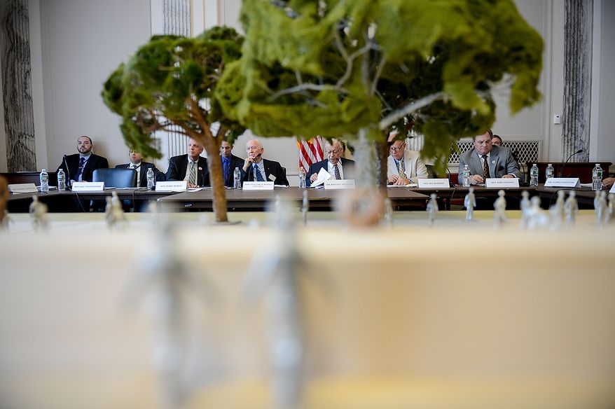 members of the Eisenhower Memorial Commission can be seen through a model of the proposed Eisenhower Memorial, displayed at a public meeting on Capitol Hill, Washington, D.C., Wednesday, June 19, 2013. The Commission met to discuss the continuing controversy over Frank Gehry's design for a memorial honoring Dwight D. Eisenhower. (Andrew Harnik/The Washington Times)