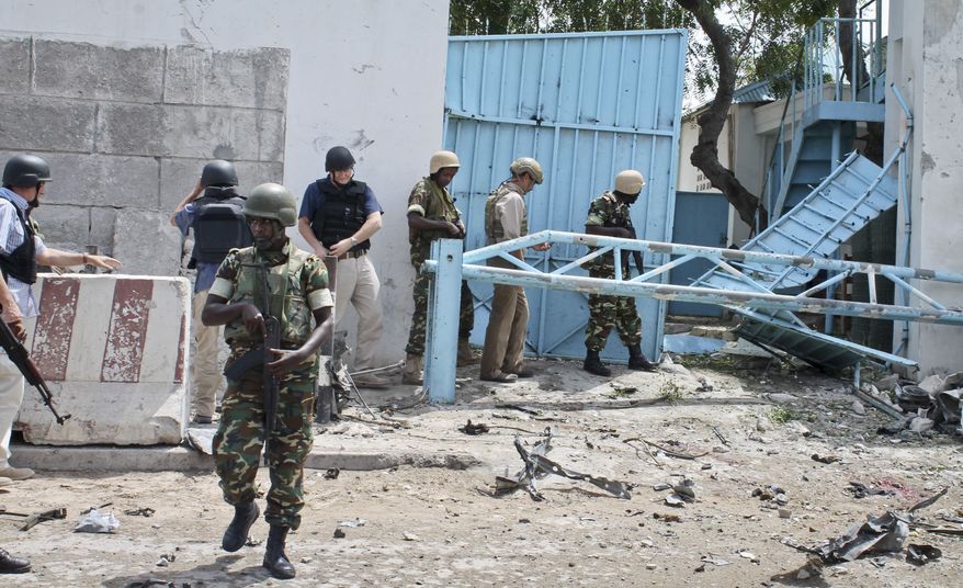 African Union peacekeepers and unidentified foreigners stand outside the main U.N. compound following an attack in Mogadishu, Somalia, on Wednesday, June 19, 2013. Al-Qaeda-linked militants detonated multiple bomb blasts and engaged in ongoing battles with security forces in an attempt to breach the compound in the Somali capital, officials said Wednesday. (AP Photo/Farah Abdi Warsameh)