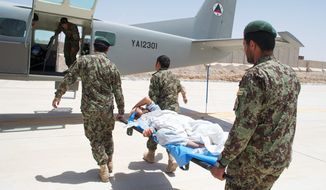 Under the careful watch of coalition advisers, members of the Kandahar Air Wing carry an injured Afghan soldier onto a Cessna 208. The Afghan air force is far from ready to take over combat responsibilities from NATO. (Kristina Wong/The Washington Times)