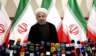 ** FILE ** Iranian newly elected President Hasan Rouhani, listens to the Iranian national anthem, before beginning a press conference, in Tehran, Iran, June 17, 2013. (AP Photo/Ebrahim Noroozi)