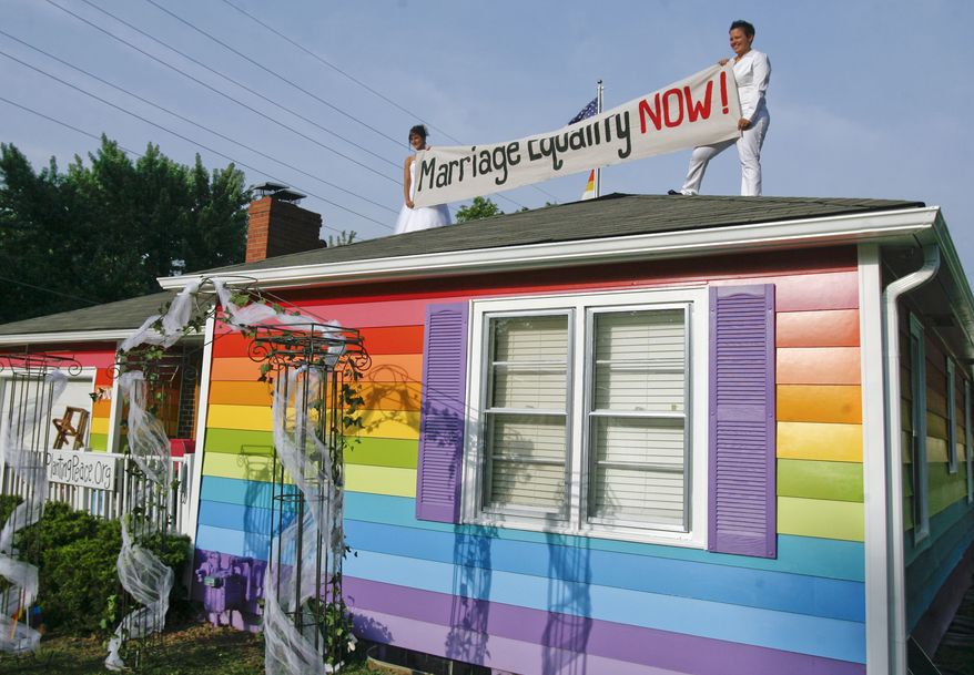 Kimberly Kidwell (right) and her partner, Katie Short, hold up a marriage equality sign on top of the Equality House before their wedding on Saturday, June 22, 2013, in Topeka, Kan. (AP Photo/The Topeka Capital Journal, Chris Neal)