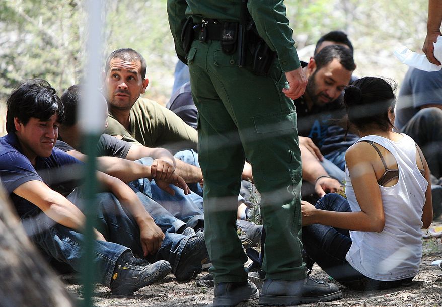 **FILE** People wait under a tree after they were detained by Border Patrol agents on June 25, 2013, at a field in Edinburg, Texas. Agents took into custody 69 people suspected of entering the country illegally. (Associated Press/The Monitor)