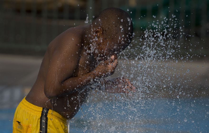 Willie Fitts, 8, holds his nose as he dips his head in the spray of a fountain at the Red Ridge Park kids water park in Las Vegas on Saturday, June 29, 2013. (AP Photo/Julie Jacobson)