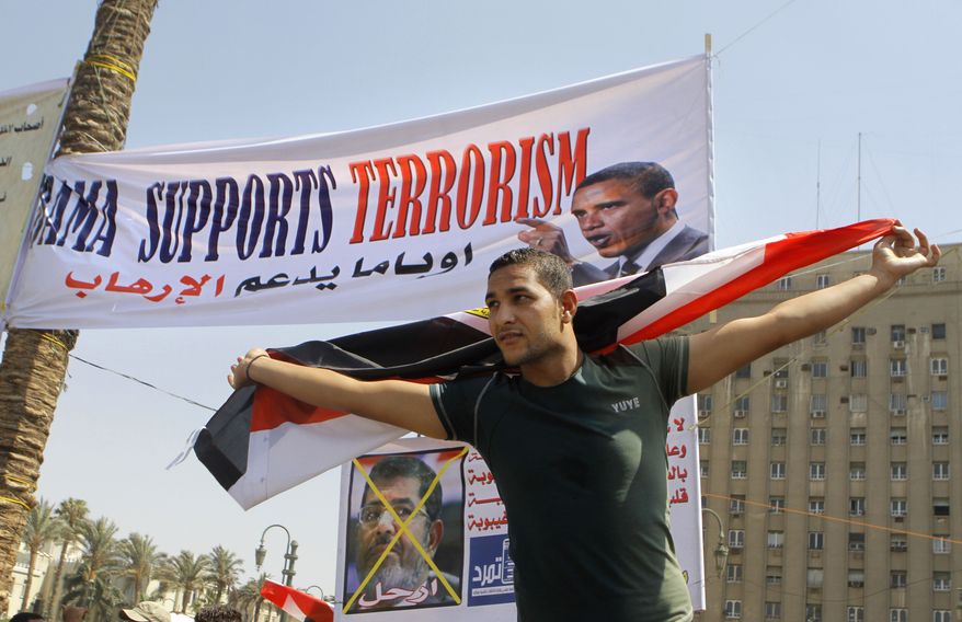 An Egyptian protesting President Mohammed Morsi waves a national flag in front of a banner criticizing Morsi and U.S. President Barack Obama in Tahrir Square, the focal point of Egyptian uprising, in Cairo on June 30, 2013. Thousands of opponents and supporters of the president began massing in city squares in competing rallies, gearing up for a day of massive nationwide protests that many fear could turn deadly as the opposition seeks to push out Mohammed Morsi. Arabic reads, "Leave." (Associated Press)