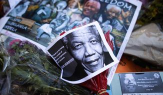 Photos, flowers and good wishes laid in support of former South African President Nelson Mandela at the entrance of the Mediclinic Heart Hospital where Nelson Mandela is being treated in Pretoria, South Africa, Tuesday, July 2, 2013. Mandela remained in a critical condition on Tuesday. (AP Photo/Markus Schreiber)