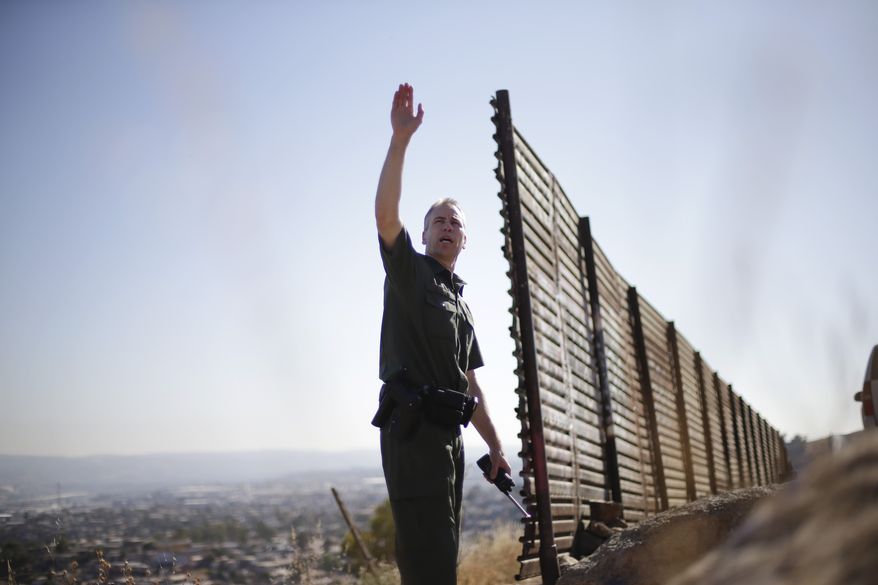 **FILE** U.S. Border Patrol agent Jerry Conlin looks out over Tijuana, Mexico, along the old border wall along the U.S.-Mexico border on June 13, 2013, where it ends at the base of a hill in San Diego. (Associated Press)