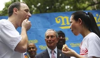 New York City Mayor Michael Bloomberg, center, watches and Joey Chestnut, left, and Sonya Thomas face off while eating a hot dog after the official weigh-in for the Nathan&#39;s Fourth of July hot dog eating contest, Wednesday, July 3, 2013 at City Hall park in New York. (AP Photo/Mary Altaffer)