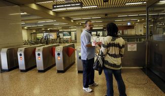 ** FILE ** BART station agent Mark Madrigal helps a customer at the Lake Merritt station in Oakland, Calif., Friday, June 28, 2013. (AP Photo/Marcio Jose Sanchez)