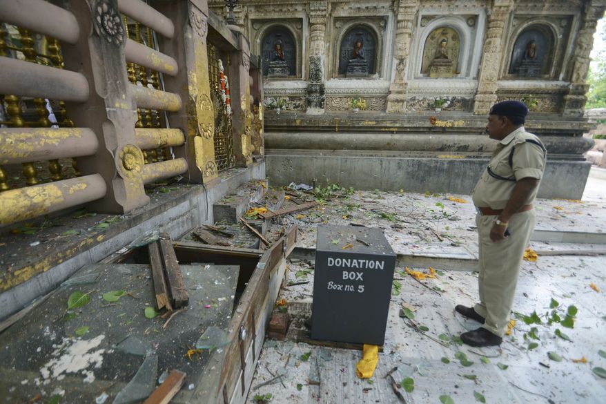 A security officer inspects the site of an explosion on the campus of the Mahabodhi Temple, the Buddhist Great Awakening temple, in Bodhgaya, about 80 miles south of Patna, the capital of the eastern Indian state of Bihar, on Sunday, July 7, 2013. A series of small blasts injured at least two people, police said. (AP Photo/Manish Bhandari)