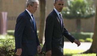 President Obama (right) walks with former President George W. Bush during a wreath-laying ceremony on Tuesday, July 2, 2013, to honor the victims of the U.S. Embassy bombing in Dar es Salaam, Tanzania. Mr. Obama was traveling in Tanzania on the final leg of his three-country tour in Africa. (AP Photo/Evan Vucci)