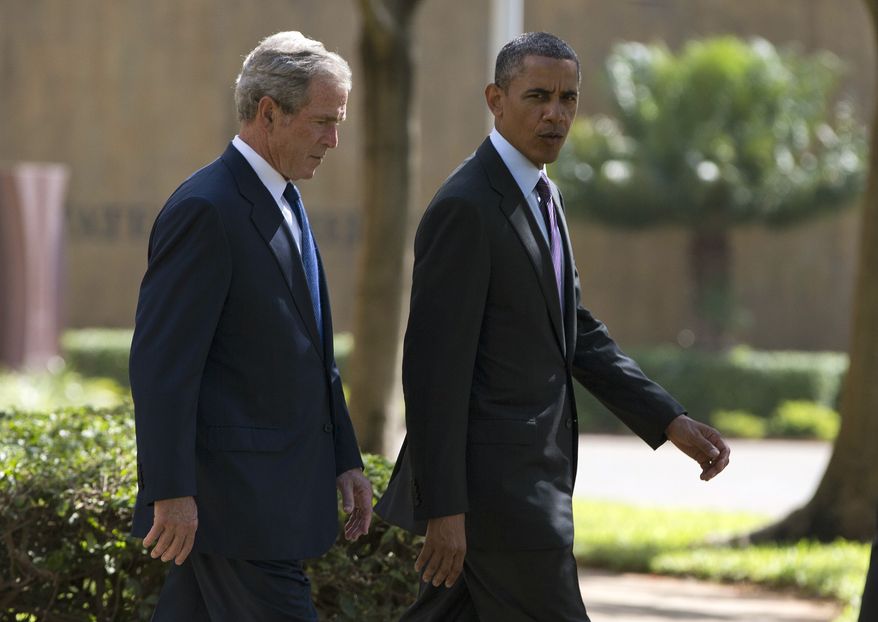 President Obama (right) walks with former President George W. Bush during a wreath-laying ceremony on Tuesday, July 2, 2013, to honor the victims of the U.S. Embassy bombing in Dar es Salaam, Tanzania. Mr. Obama was traveling in Tanzania on the final leg of his three-country tour in Africa. (AP Photo/Evan Vucci)