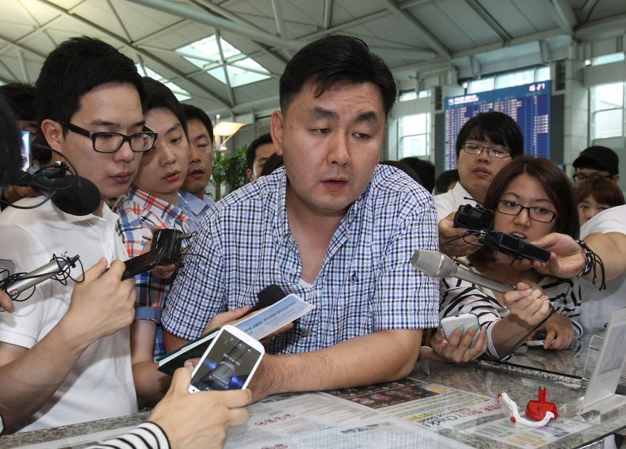 Geum Jae-kook (center), a relative of a passenger injured when an Asiana Airlines plane crashed Saturday in San Francisco, checks in at the Incheon International Airport in Incheon, South Korea, on Sunday, July 7, 2013, before boarding his flight for the United States to meet his family member. (AP Photo/Ahn Young-joon)