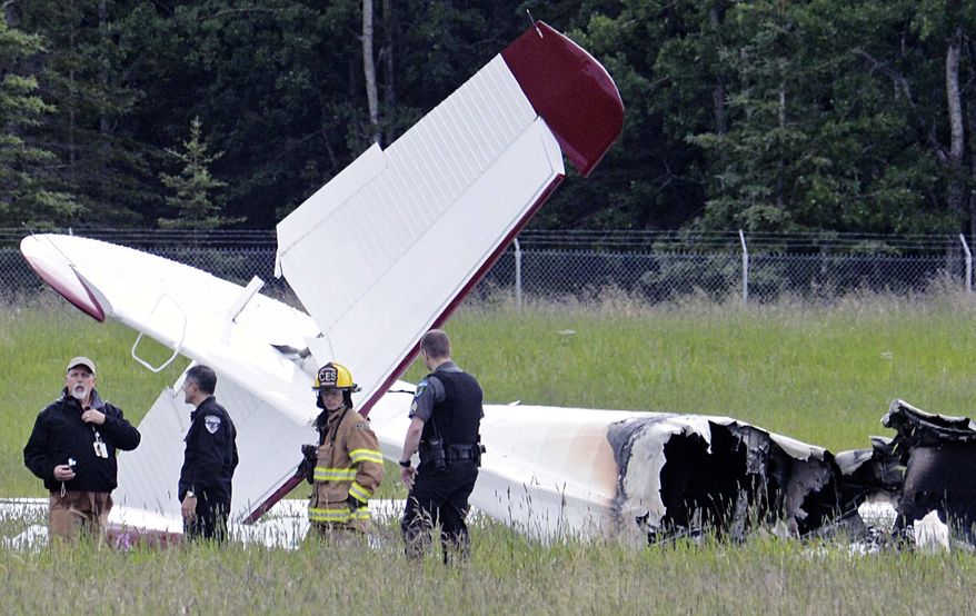 Police and emergency personnel stand near the remains of a fixed-wing aircraft that was engulfed in flames Sunday July 7, 2013, at the Soldotna Airport in Soldotna, Alaska. There were no survivors. (AP Photo/Peninsula Clarion, Rashah McChesney)