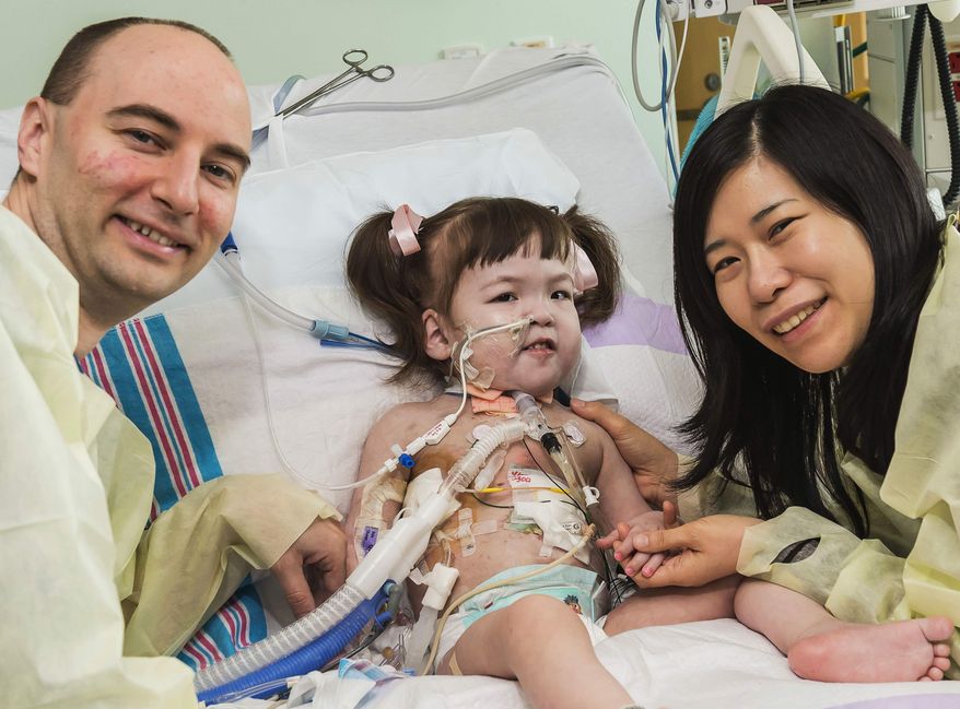 ** FILE ** In this April 26, 2013, file photo provided by OSF Saint Francis Medical Center in Peoria, Ill., Darryl Warren and Lee Young-mi visit with their 2-year-old daughter Hannah Warren in a post-op room at Children's Hospital of Illinois in Peoria after having received a new windpipe in a landmark transplant operation April 9, 2013. Hannah died Saturday, July 6, 2013. She was the youngest patient in the world to benefit from the experimental treatment. (AP Photo/OSF Saint Francis Medical Center, Jim Carlson, File)
