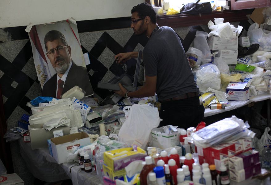 An Egyptian medic supporter of ousted President Mohammed Morsi, works at a field hospital in Nassr City in Cairo, Egypt, Monday, July 8, 2013. Egyptian soldiers and police opened fire on supporters of the ousted president early Monday in violence that left dozens of people killed, including one officer, outside a military building in Cairo where demonstrators had been holding a sit-in, government officials and witnesses said. (AP Photo/Khalil Hamra)