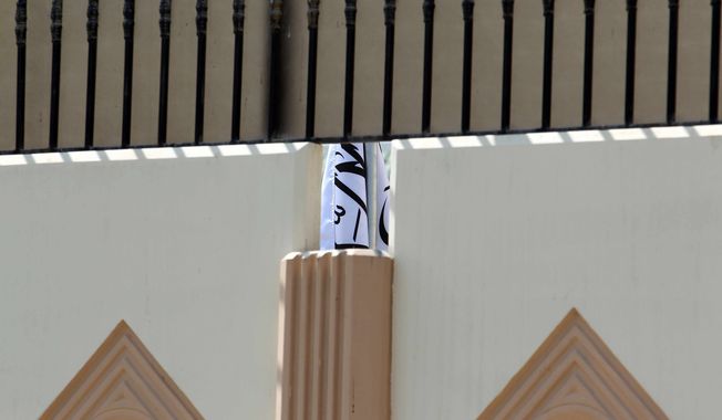This photo was taken on Thursday, June 20, 2013, shows the Taliban flag visible through a gap in a wall of the new office of the Afghan Taliban in Doha, Qatar, after the opening of the office several days ago. (AP Photo/Osama Faisal)