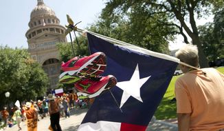 ** FILE ** Karen McCrocklin of Dallas carries a Texas flag with pink running shoes similar to those worn by state Sen. Wendy Davis during the previous week&#39;s filibuster during a pro-abortion rights rally at the state Capitol in Austin, Texas, on Monday, July 1, 2013. (AP Photo/Statesman.com, Jay Janner)
