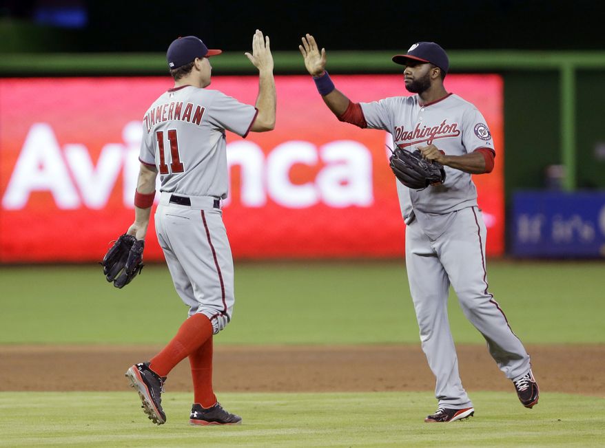 Washington Nationals third baseman Ryan Zimmerman, left, celebrates with center fielder Denard Span, right, after the Nationals defeated the Miami Marlins 5-2 in 10 innings of a baseball game, Sunday, July 14, 2013 in Miami. Span had three hits, including a tie breaking two-out RBI double in the 10th inning. (AP Photo/Wilfredo Lee)