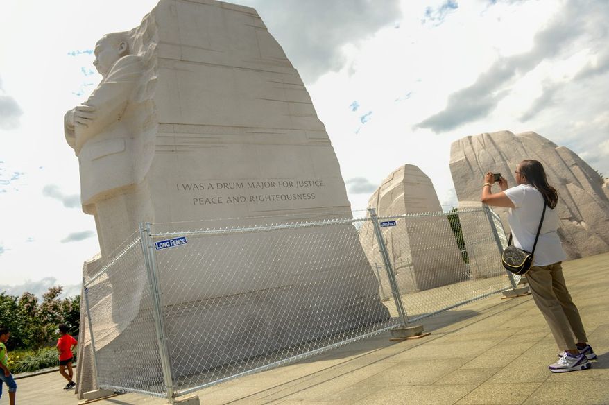 Earlene Purches of Flint, Mich., takes a photograph of the Martin Luther King Jr. Memorial on Monday. Work to remove a paraphrased quote from the memorial has begun and is expected to last three to four weeks. (Andrew Harnik/The Washington Times)