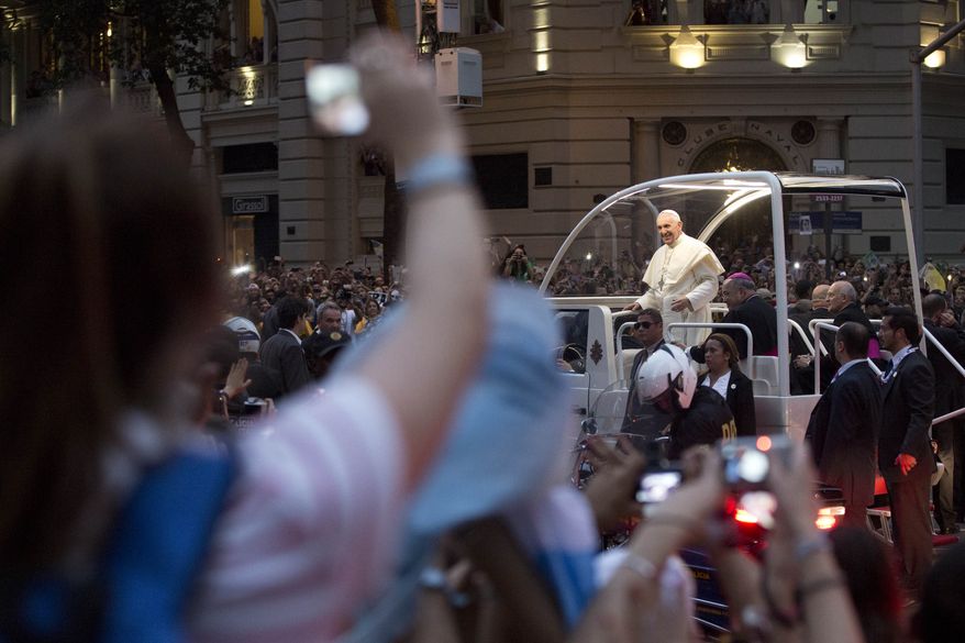 Pope Francis makes his way in a popemobile into central Rio de Janeiro, Brazil, Monday, July 22, 2013. The pontiff arrived for a seven-day visit in Brazil, the world's most populous Roman Catholic nation. During his visit, Francis will meet with legions of young Roman Catholics converging on Rio for the church's World Youth Day festival.(AP Photo/Felipe Dana)