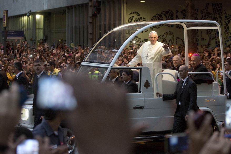 Pope Francis waves from his popemobile as he makes his way into central Rio de Janeiro, Brazil, Monday, July 22, 2013. The pontiff arrived for a seven-day visit in Brazil, the world's most populous Roman Catholic nation. During his visit, Francis will meet with legions of young Roman Catholics converging on Rio for the church's World Youth Day festival.(AP Photo/Felipe Dana)