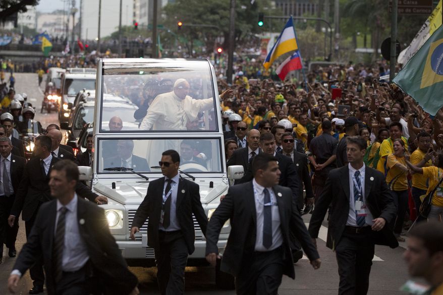 Pope Francis waves from his popemobile as he make his way into central Rio de Janeiro, Brazil, Monday, July 22, 2013. The pontiff arrived for a seven-day visit in Brazil, the world's most populous Roman Catholic nation. During his visit, Francis will meet with legions of young Roman Catholics converging on Rio for the church's World Youth Day festival.(AP Photo/Felipe Dana)