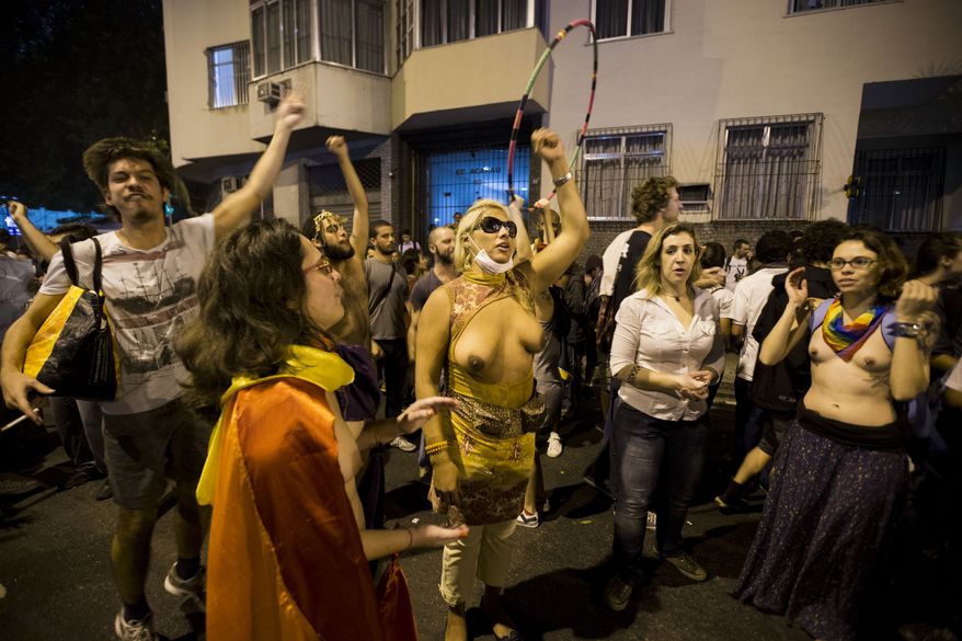 Topless protesters belonging to a gay, lesbian and transgender group, demonstrate near Guanabara Palace in Rio de Janeiro, Brazil on Monday, July 22, 2013. Police and anti-government protesters clashed outside the palace hosting the pope's welcoming ceremony. About an hour after the pope concluded his short speech, police began cracking down on the protests, firing rubber bullets in an effort to disperse the crowd.(AP Photo/Victor R. Caivano)