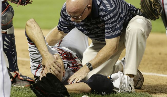Atlanta Braves' Tim Hudson is helped by a trainer after being injured on a play at first base during the eighth inning of a baseball game against the New York Mets, Wednesday, July 24, 2013, in New York. (AP Photo/Frank Franklin II)