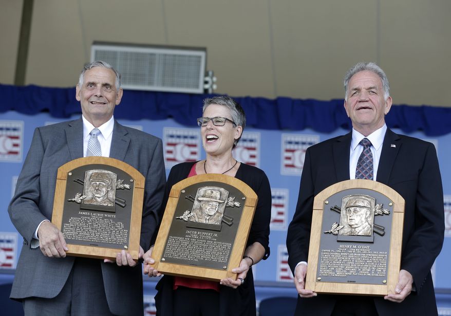 Family representatives Jerry Watkins, left, great grandson of Baseball Hall of Fame inductee Deacon White, Anne Vernon, center, great grandniece of inductee Jacob Ruppert, and Dennis McNamara, grandnephew of inductee Hank O'Day, hold the players' plaques after a ceremony on Sunday, July 28, 2013, in Cooperstown, N.Y. (AP Photo/Mike Groll)