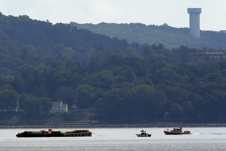 Rescue workers on boats search near a construction barge (left) on the Hudson River in Piermont, N.Y., on Saturday, July 27, 2013, south of the Tappan Zee Bridge after two people fell into the water during a boat crash. A woman's body was recovered, and authorities still are searching for a man, who is presumed dead. (AP Photo/Julio Cortez)